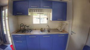 a small kitchen with blue cabinets and a sink at Camping Prima in Týn nad Vltavou