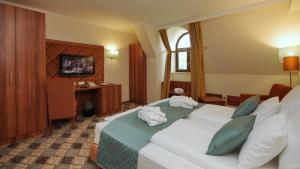 a hotel room with a bed and a television at Wellness Hotel Gyula in Gyula