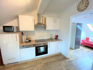 a kitchen with white cabinets and a clock on the wall at Ferienwohnung Denise in Rötz