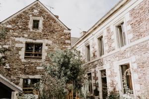 um antigo edifício de tijolos ao lado de dois edifícios mais antigos em Le Logis des Mariniers em Chalonnes-sur-Loire