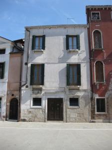 a white building with green shutters on a street at Casa Renata in Venice