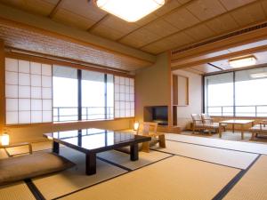 a room with a table and chairs and windows at Kagaya in Nanao