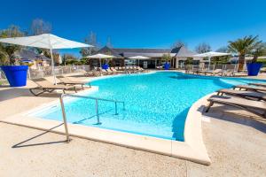 Langrune-sur-Mer的住宿－M&V Resort Camping，一个带椅子和遮阳伞的大型游泳池