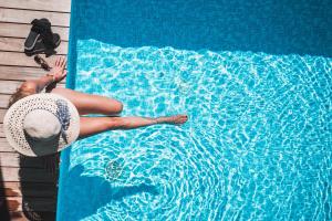una mujer con sombrero tendida en un lado de una piscina en Hotel Am Sonneck, en Lagundo