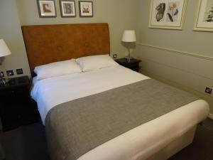 a bedroom with a large bed with white sheets at The Belmore in Sale