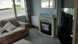 ein Wohnzimmer mit einem Sofa und einem Kamin in der Unterkunft Static Caravan for hire, budget friendly in Edinburgh