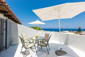 un patio con mesa, sillas y sombrilla en Philoxenia Apartments, en Panormos Rethymno