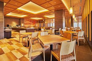 京都市にあるホテル エミオン 京都の木製のテーブルと椅子、キッチンが備わるレストラン