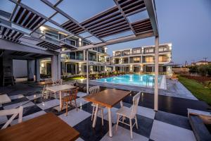 an outdoor patio with tables and a swimming pool at Calda Resort in Kalivia Poligirou