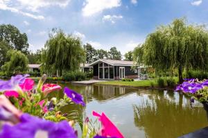 uma casa com um lago e flores em frente em TopParken – Résidence Lichtenvoorde em Lichtenvoorde