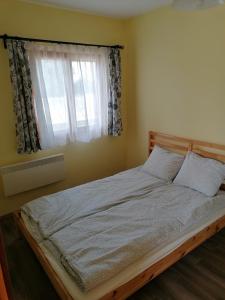 a bed in a bedroom with a window at Piliscsévi Vendégház in Piliscsév