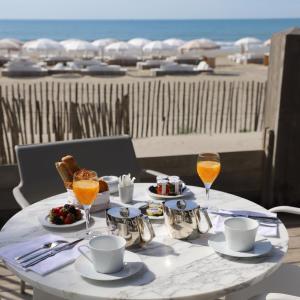 uma mesa branca com comida e bebidas na praia em Hôtel Plage Palace & Spa em Palavas-les-Flots