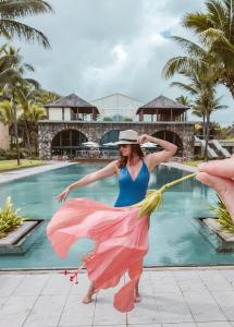 a woman in a pink dress holding a pink umbrella at Outrigger Mauritius Beach Resort in Bel Ombre