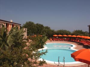 a swimming pool with orange umbrellas and chairs around it at Residence Baia Infreschi in Marina di Camerota