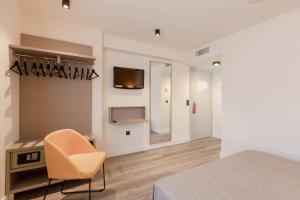 a room with a bed and a chair and a television at Hotel Zeus in Málaga