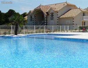 a large blue swimming pool in front of a house at PAREE D EAU 104 - Résidence avec piscine - Appartement rez de jardin 1 chambre in Notre-Dame-de-Monts