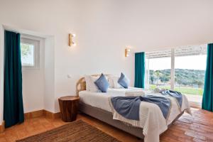 a bedroom with a bed with blue curtains and a window at Herdade do Barrocal de Baixo in Montemor-o-Novo