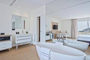 a white bathroom with white furniture and a tub at Melia Sitges in Sitges