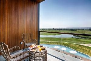 a balcony with a table and chairs and a pool at Empordà Golf Resort in Torroella de Montgrí