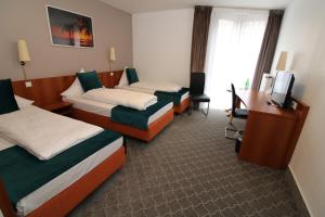 a hotel room with two beds and a desk at Concorde Hotel Ascot in Düsseldorf