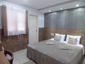 1 dormitorio con 1 cama grande y pared de madera en Hotel Visão en Ivoti