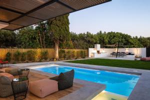 a swimming pool in a backyard with a table and chairs at Physis Villas - Metal & Wood in Pigi