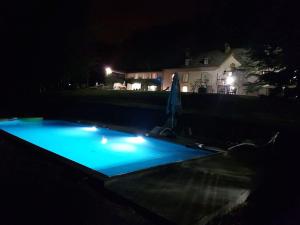 uma piscina à noite com luzes azuis em Le Clos Cathala Chambres d'Hôtes em Saint-Paul-de-Jarrat