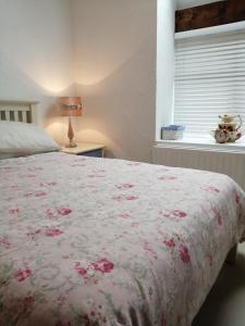 a bedroom with a bed with a floral bedspread and a window at Killarney Saoirse Cottage in Killarney