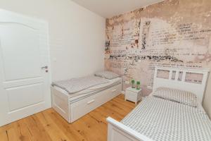 a bedroom with two beds and a wall with writing at Dalomar Apartment in Biograd na Moru