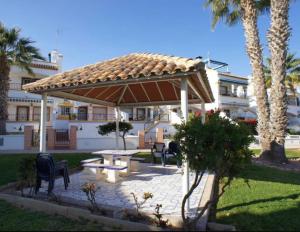 een prieel met een picknicktafel en stoelen en palmbomen bij Bungalow Los Dolses in Orihuela