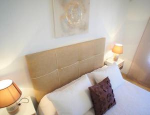 een bed met witte kussens en 2 lampen in een kamer bij Bungalow Los Dolses in Orihuela