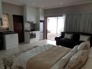 Pongola Road Self Catering Accommodation في Uitenhage: غرفة نوم بسرير كبير وغرفة معيشة