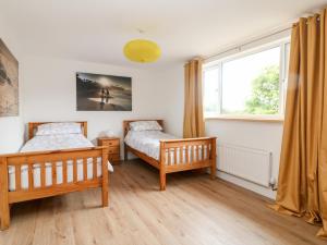 a bedroom with two beds and a window at Pen Chy in Helston
