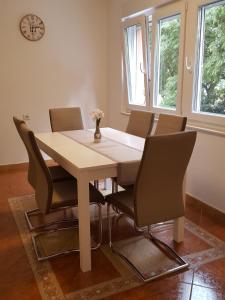 a dining room table with chairs and a clock on the wall at Harmony apartment in Rijeka +23 photos