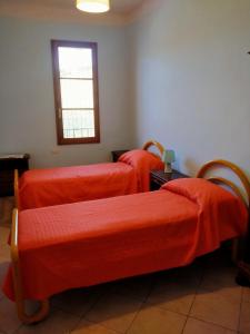 a room with three beds with orange sheets at Agriturismo I due Falcetti in Castelfiorentino