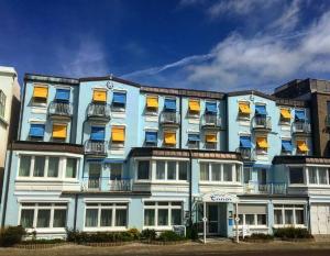 a blue building with windows and a clock on it at Hotel Restaurant Ennen in Norderney