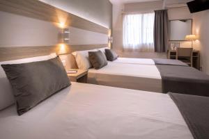 Pokój hotelowy z 2 łóżkami i biurkiem w obiekcie Hotel Catalunya Express w mieście Tarragona
