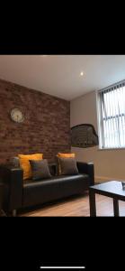 a living room with a couch and a brick wall at Spacious Shude Hill Apartment With Balcony in Manchester