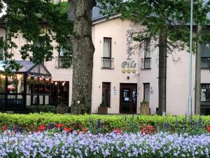 a white building with flowers in front of it at Hotel Pils with Self-Check in in Sigulda