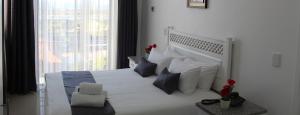 Royal Ushaka Hotel Morningside في ديربان: غرفة نوم بسرير ابيض مع مخدات ونافذة