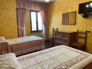 a bedroom with two beds and a desk and a mirror at Hostería Carmen in Santillana del Mar