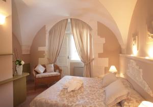 a bedroom with a bed and a window and a chair at Hotel Park Novecento Resort in Ostuni