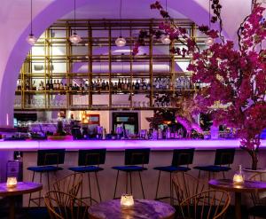 a bar with tables and chairs in a room with purple lighting at The TownHouse Mykonos in Mikonos