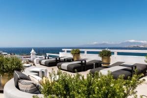 a rooftop patio with black and white furniture and the ocean at The TownHouse Mykonos in Mikonos
