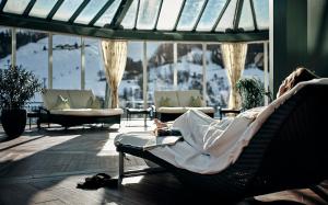 a person laying in a chair with a book at Hotel Pichlmayrgut in Schladming