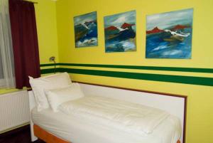 a bedroom with a white bed with paintings on the wall at Hotel Residenz Hössinger in Sankt Pölten