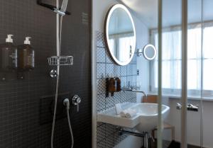 a bathroom with a shower, sink, and mirror at Marktgasse Hotel in Zurich