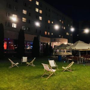 a group of lawn chairs in front of a building at night at Żaczek Hotele Studenckie in Krakow