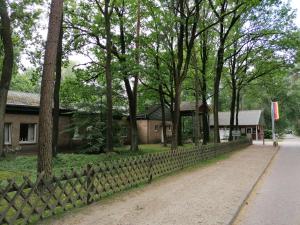 a fence in front of a house with trees at Waldjugendherberge Uelsen in Uelsen