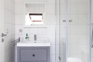 een witte badkamer met een wastafel en een douche bij Ferienwohnung Quedlinburg Harz in Quedlinburg